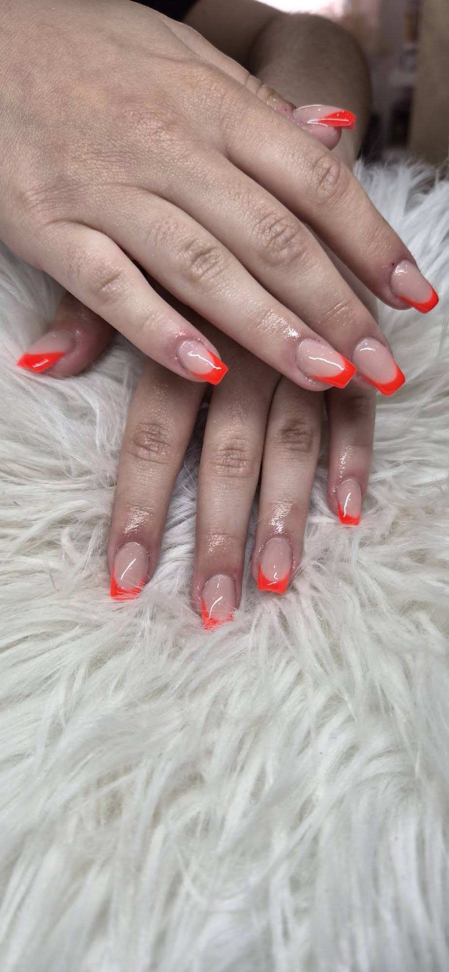 Vivid coral French tip nails on white fluffy backdrop